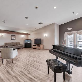 A spacious and modern living room featuring a piano, comfortable seating, and a large TV.