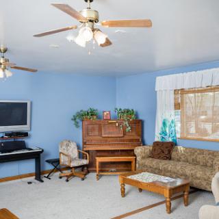 A cozy living room featuring a piano, comfortable sofa, and blue walls.