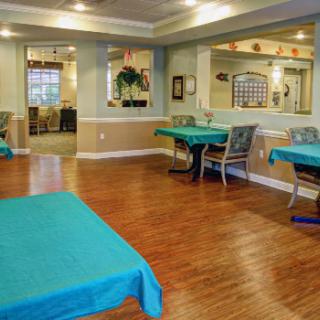An indoor dining area with neatly arranged tables and chairs on a wooden floor.