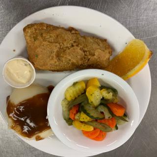 A well-balanced dinner plate featuring fried chicken, mixed vegetables, and a side of sauce with a slice of orange.