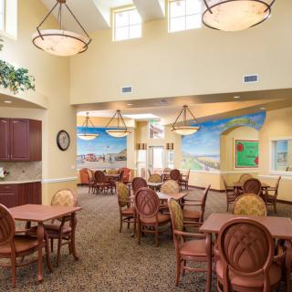 A spacious dining area with neatly arranged tables and chairs, featuring decorative murals and modern lighting.