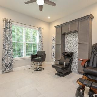 A modern interior featuring barber chairs and stylish cabinetry, complemented by large windows with patterned curtains.