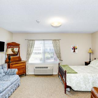 A cozy bedroom with a bed, sofa, and wooden furniture.