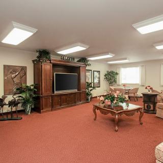 A cozy living room with a large TV, sofas, and plants for decoration.