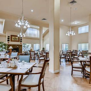 A cozy dining area with neatly arranged tables and chairs, featuring elegant lighting fixtures.