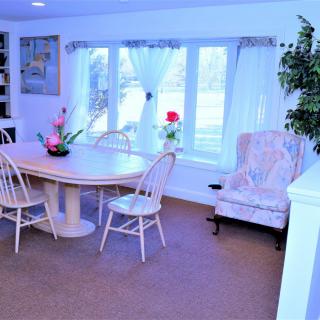 A cozy dining room with a table, chairs, and large windows adorned with curtains.