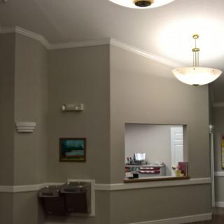 A waiting room with a reception window, water fountain, and decorative lighting.