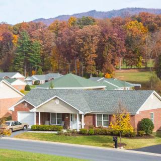 A suburban neighborhood with houses surrounded by colorful autumn trees and mountains in the background.