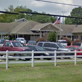 A view of a building with several cars parked in front, featuring an American flag.