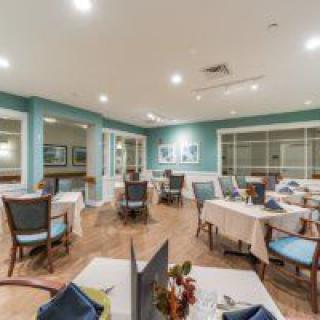 A well-arranged dining area with several tables and chairs, featuring elegant decor and soft lighting.