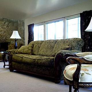 A cozy living room with a patterned sofa, two lamps, and a window letting in natural light.