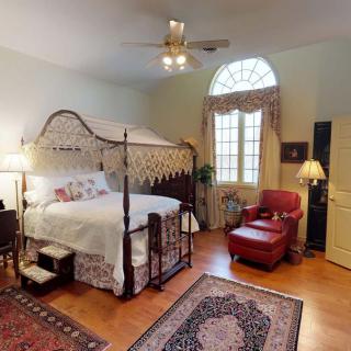 A cozy vintage-style bedroom featuring a four-poster bed and a comfortable armchair.
