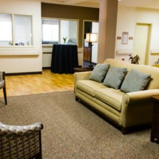 A cozy waiting room with a sofa, armchairs, and carpet flooring.
