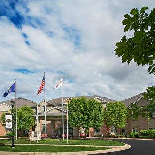 A building entrance with flags and surrounding trees under a cloudy sky.