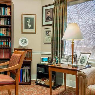 A cozy office space with a bookshelf, desk, and comfortable seating.