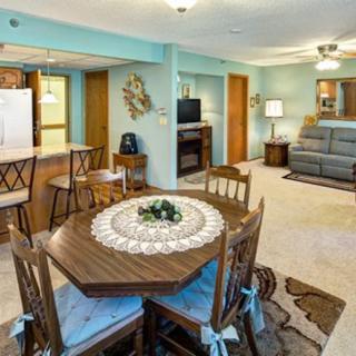 A cozy open-floor plan living space features a dining area with a wooden table and chairs, adjacent to a comfortable living room with a sofa and television.