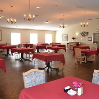 A spacious dining area with red tablecloths set for guests.