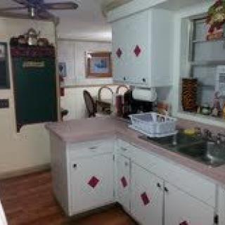 A cozy kitchen with white cabinets and a countertop, featuring a dish rack by the sink.