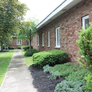 A brick building with a well-maintained pathway and lush greenery.