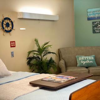A cozy and welcoming healthcare room featuring a bed, comfortable sofa, and decorative elements.