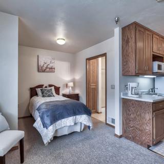 A cozy studio apartment featuring a bed and a compact kitchenette.