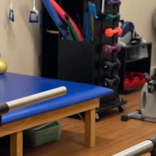 A physical therapy room with various exercise equipment and a treatment table.