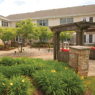 A well-maintained courtyard garden with lush greenery and a brick structure.