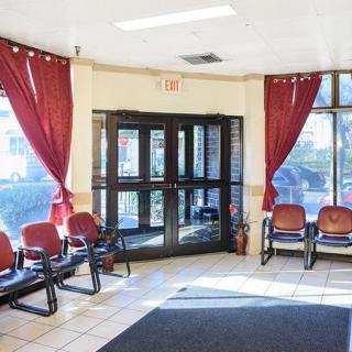 An empty waiting room with rows of chairs and sunlight streaming through the windows.
