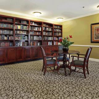 A cozy library corner with a large bookshelf and a small table surrounded by chairs.