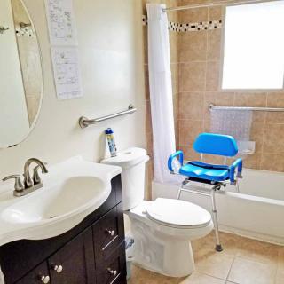 A clean and accessible bathroom with a blue shower chair in the bathtub.