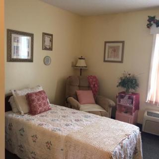 A cozy bedroom with a single bed, armchair, and decorative elements.