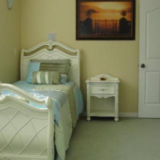 A cozy bedroom with a single bed, nightstand, and wall painting.
