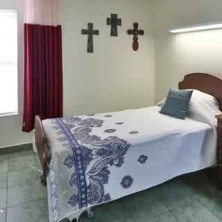A simple bedroom with a single bed and decorative crosses on the wall.
