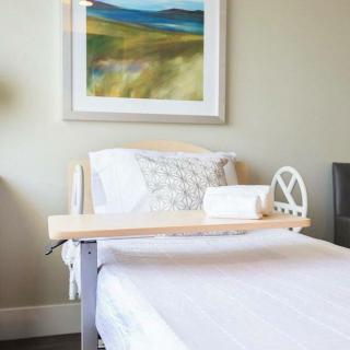 A neatly arranged hospital bed with a side table in a well-lit room featuring modern artwork.