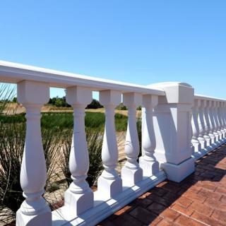 A white balustrade with a bright sunny landscape in the background.