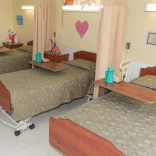 A hospital room with multiple beds separated by curtains, equipped for patient care.