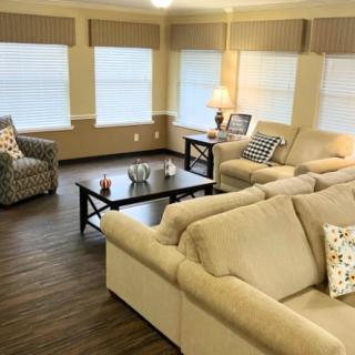 A cozy living room with beige sofas, a coffee table, and large windows.