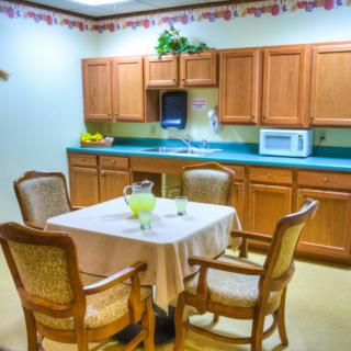 A cozy kitchen area with a table and chairs, wooden cabinets, and a microwave.