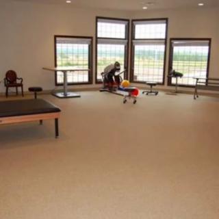 A spacious room with large windows, tables, and carpeted flooring.