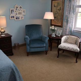 A cozy bedroom corner with a blue armchair and decorative elements.