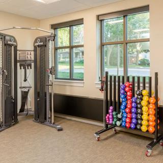 A compact gym space equipped with various dumbbells and an exercise machine.
