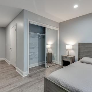 A modern minimalist bedroom featuring gray walls, laminate flooring, and stylish furnishings.