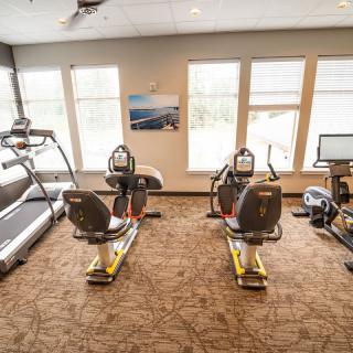 A well-lit gym with exercise equipment including treadmills and stationary bikes.