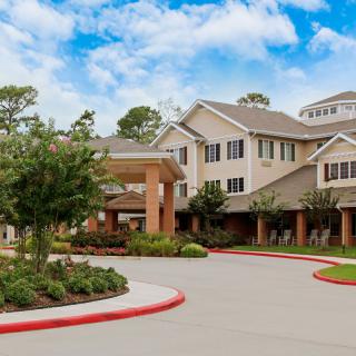 A well-maintained retirement home surrounded by lush landscaping and a clear blue sky.