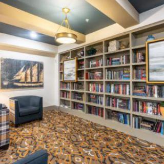 A cozy library space with bookshelves, an armchair, and decorative paintings.