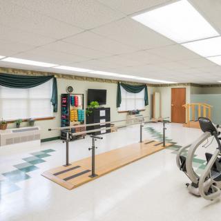 A well-equipped rehabilitation room with exercise machines and parallel bars.