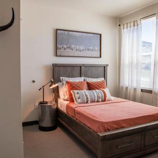 A modern bedroom with a neatly made bed, soft lighting, and artwork on the wall.