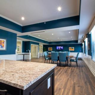 A modern conference or dining room with blue walls, wooden floors, and a large table surrounded by chairs.