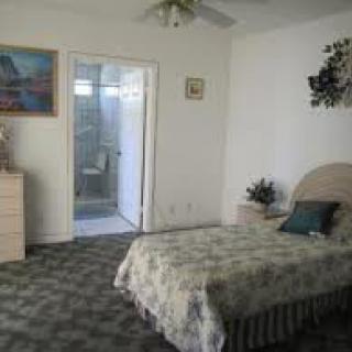A cozy bedroom with a bed, carpeted floor, and attached bathroom.