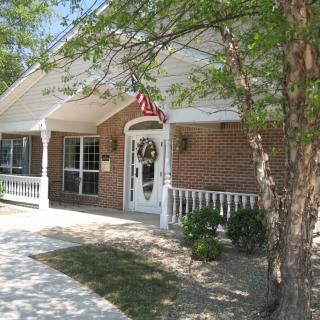 A brick house with a welcoming front porch, adorned with a wreath on the door and an American flag above.